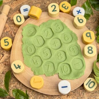 number stamping stones on a board with numbers stamped in green playdough