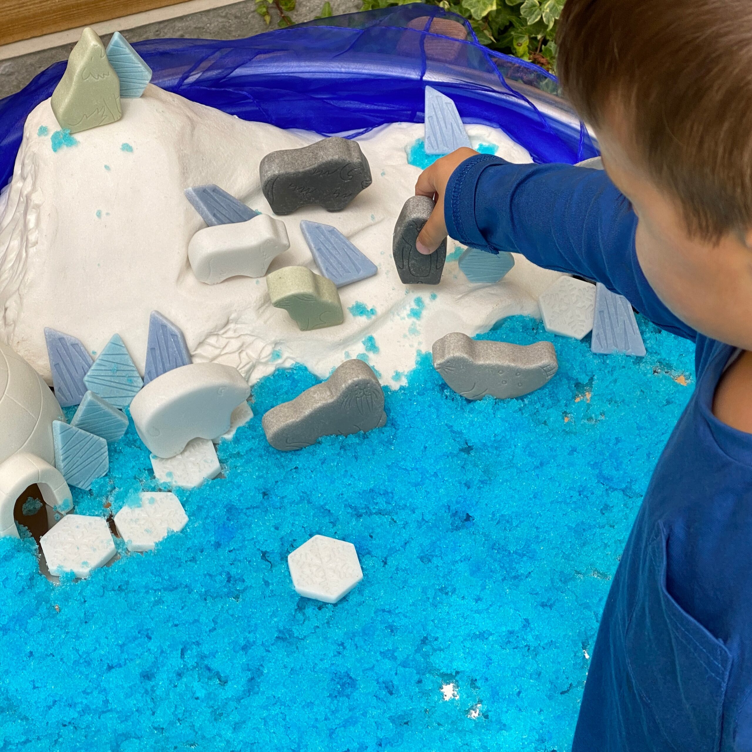 Boy enjoing messy play with polar scene imaginative play