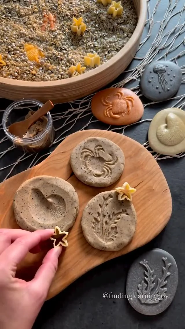 🦀🐚 Searching the sands for hidden treasures… What a magical sensory invitation from @findingcreativejoy! 🐚 🌊

With sparkling sand play dough and hidden seashore stones, this setup brings all the wonder of the beach right to your play space. Children can dig, discover, and press each treasure into the dough, revealing the delicate textures of shells, seaweed, and shoreline creatures like jellyfish and starfish.

This kind of hands-on exploration is a wonderful way to spark conversations about marine life and natural habitats — all while engaging fine motor skills and sensory curiosity. 

We love how our @yellow_door_education seashore stones made such striking impressions in the sparkly @hippiehooray dough - a perfect blend of learning and play.

🏝️ How do you bring the beach to your little ones?

#sensoryplay #playdoughfun #natureinspiredplay #beachplay #smallworldplay #montessoriinspired #earlyyearslearning #handsonlearning #yellowdooreducation #loosepartsplay #imaginativeplay #playideasforkids #natureplay #sensoryplayideas #homeschoolplay #coastalcreatures #learningthroughplay